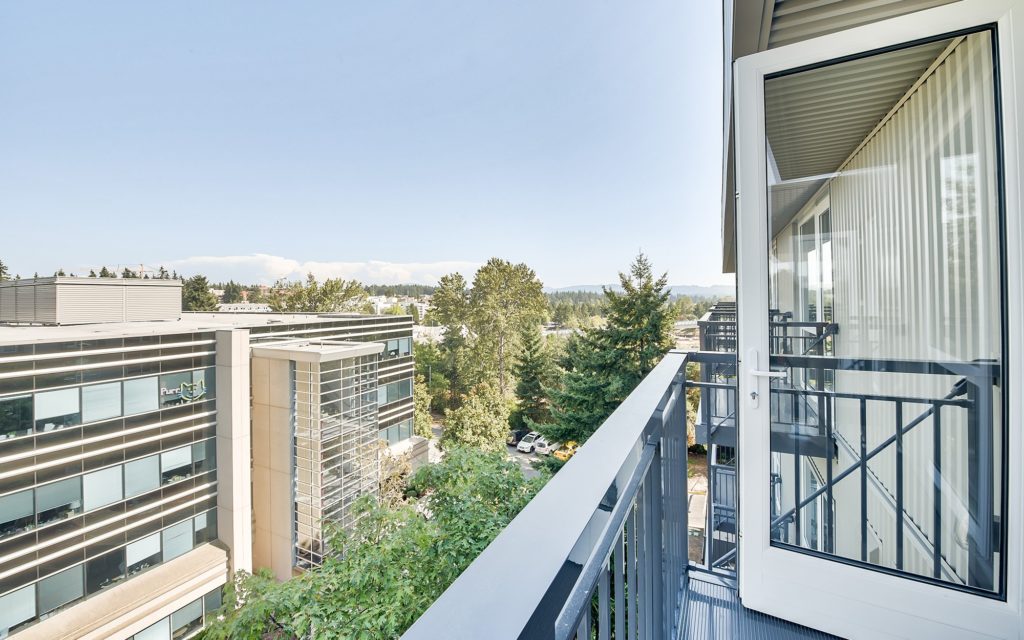 Top floor balcony view with trees and mountains in the distance